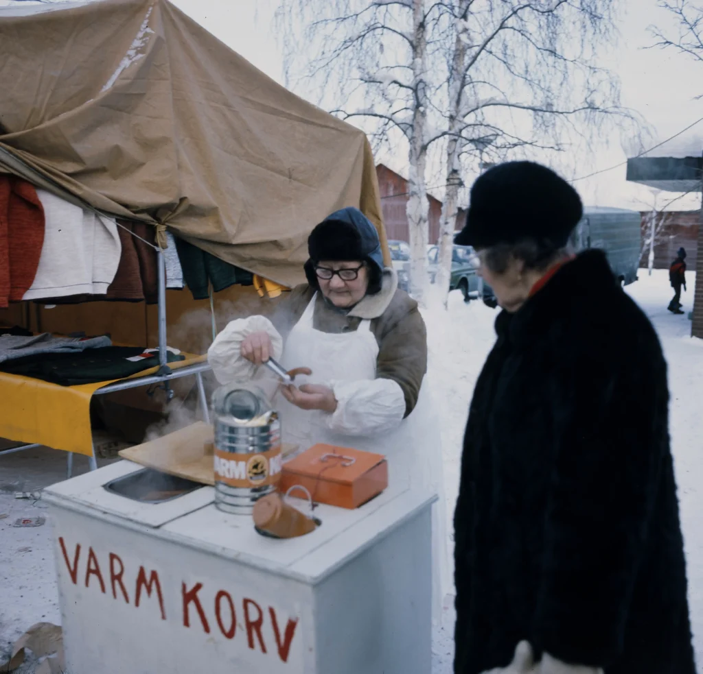 En kvinna säljer korv på Jokkmokks marknad.