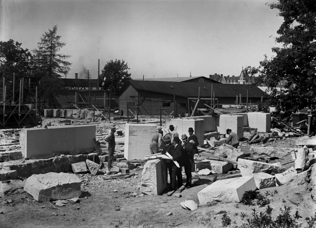 A construction site with stone blocks and mortar, and a few men in the center.