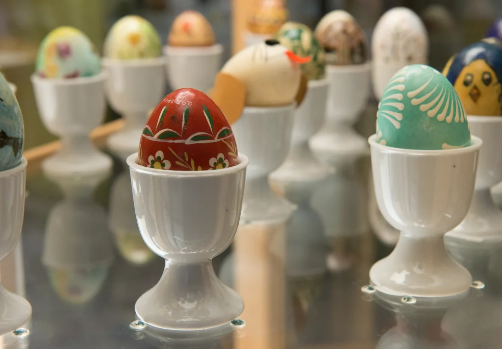Färgglada målade ägg i vita äggkoppar av porslin.