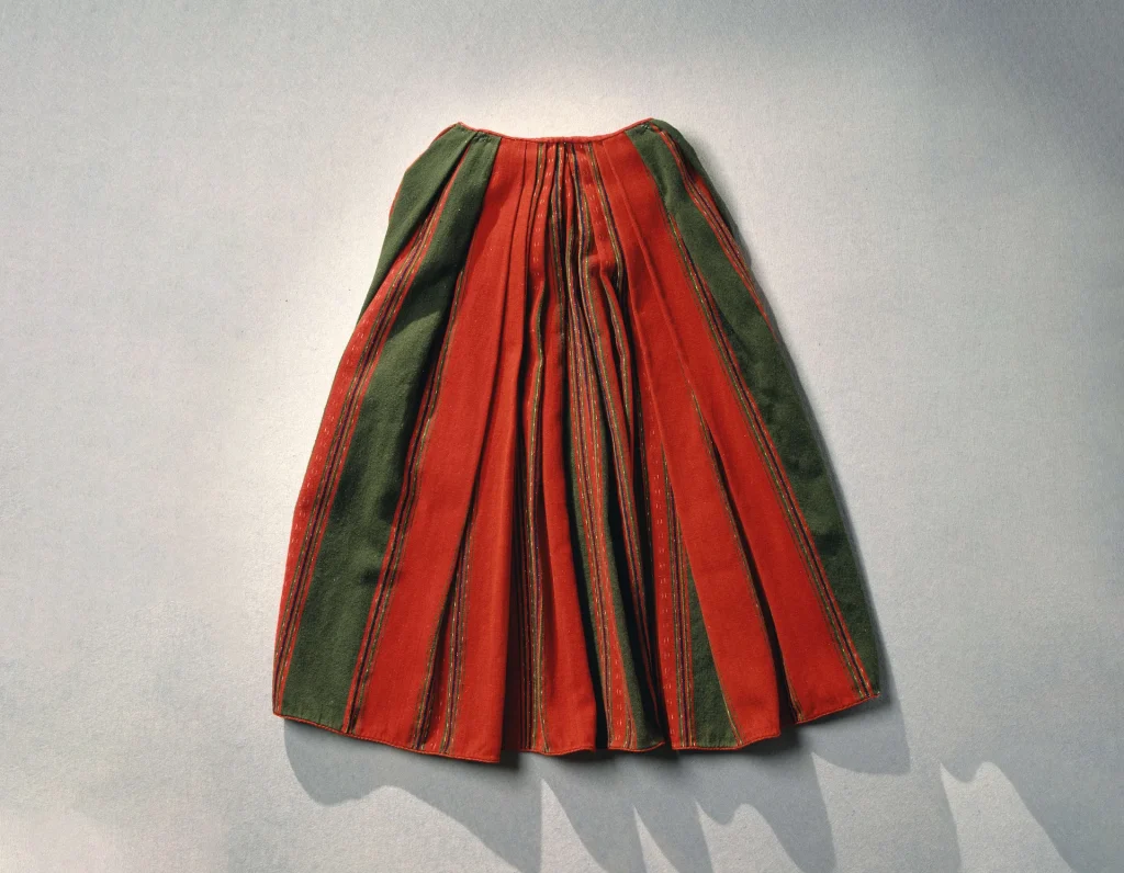 A red and green striped pleated wool skirt lies on a white background.