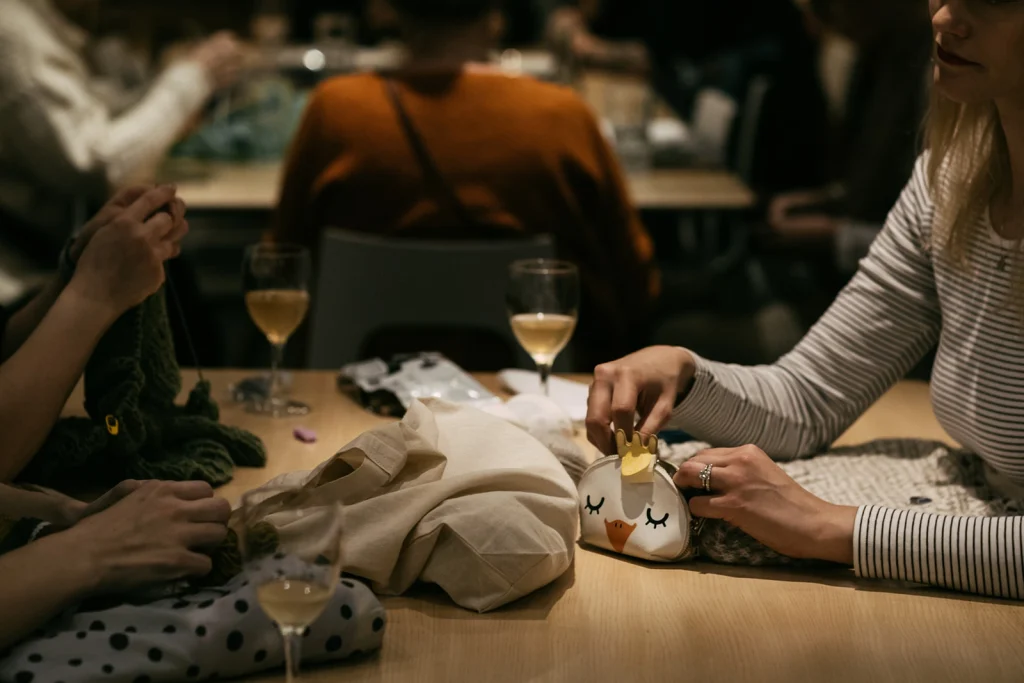 Ett restaurangbord med vinglas och händer som stickar och syr.