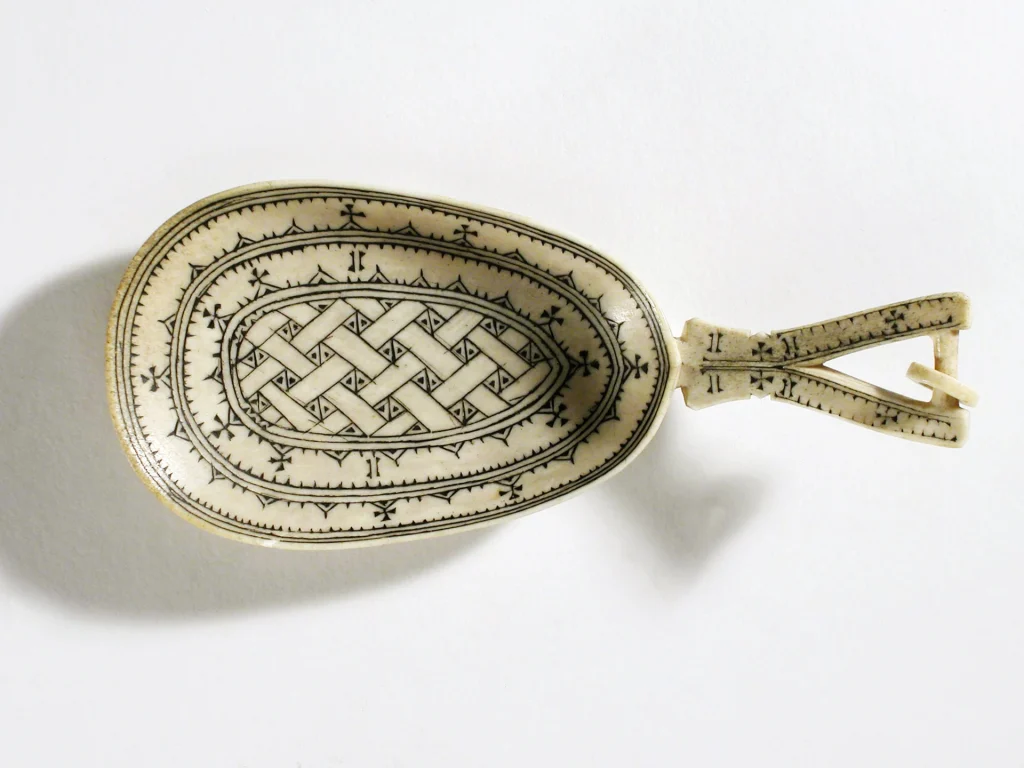 En sked i älghorn med handtag dekorerad med ett flätat mönster.