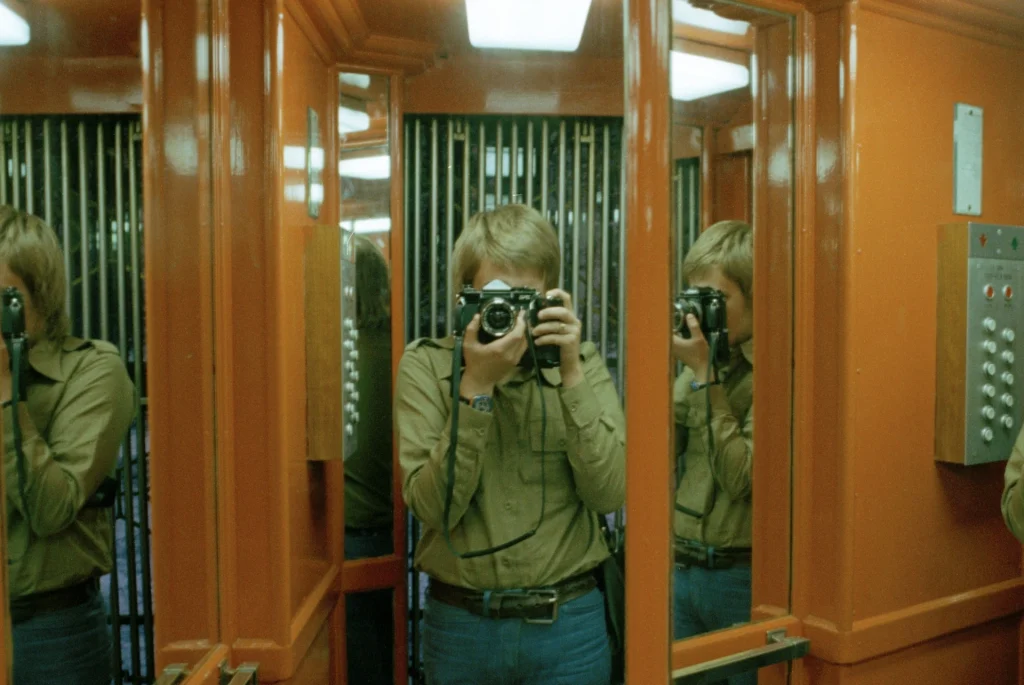 Man fotograferar i en hiss med speglar.