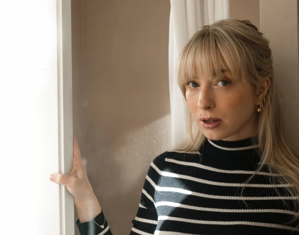 En kvinna med långt ljust hår och randig polotröja