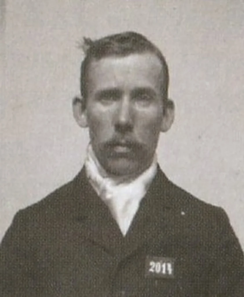 Porträtt av Alfred Ander, mustaschprydd man med kavja och vit krage.