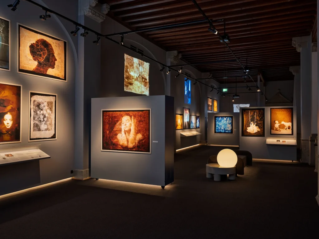 En helheltsbild över ett stort galleri med bilder i storformat längs väggarna.