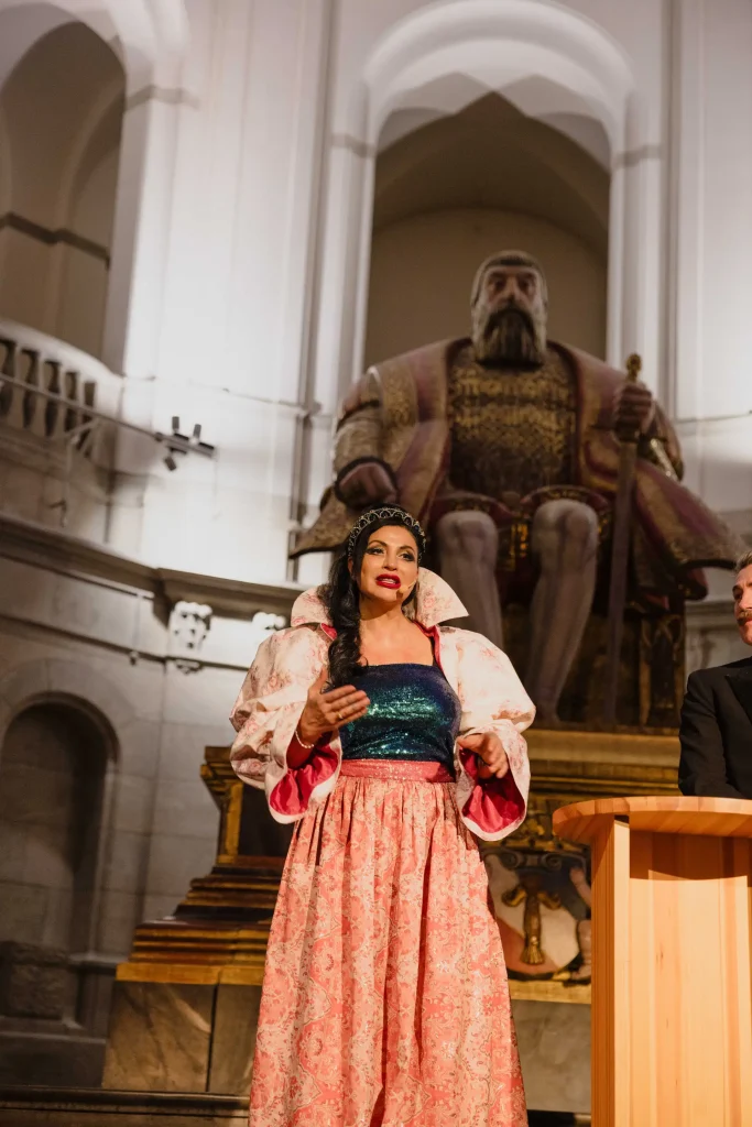 En festklädd kvinna talar på en scen.