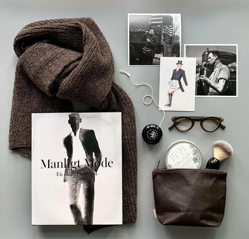 en halsduk, vykort, glasögon, rakprylar och ebok med titeln Manligt mode