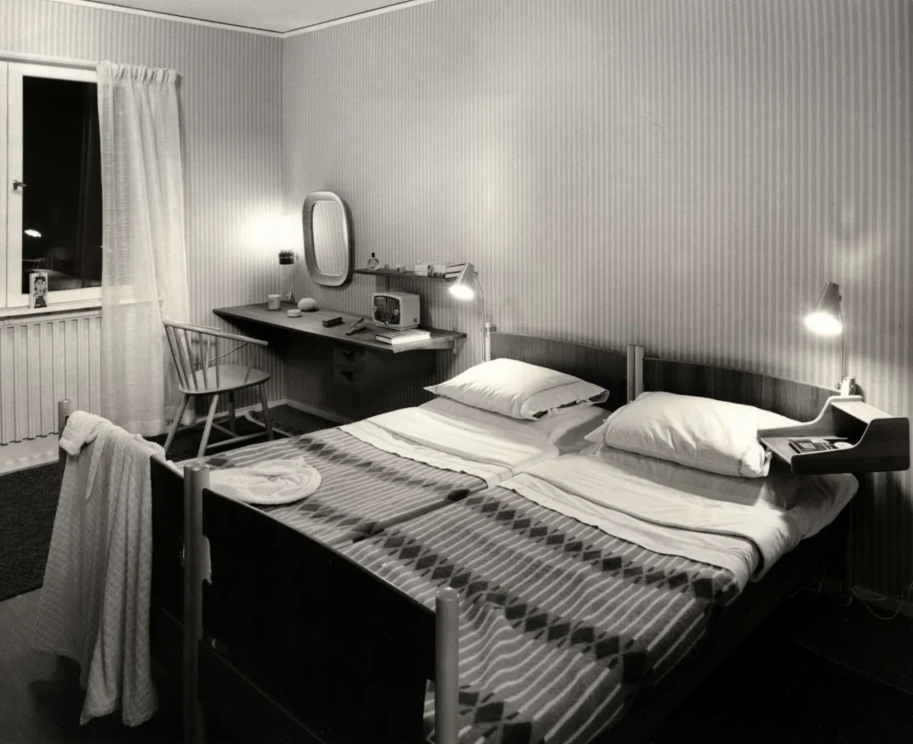 Bäddad dubbelsäng med sängbord vid vardera sida.