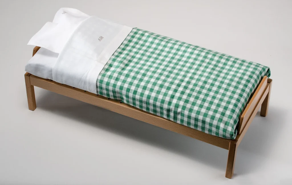 Närbild av en modellsäng med grönt och vitrutigt påslakan och vitt örngott.