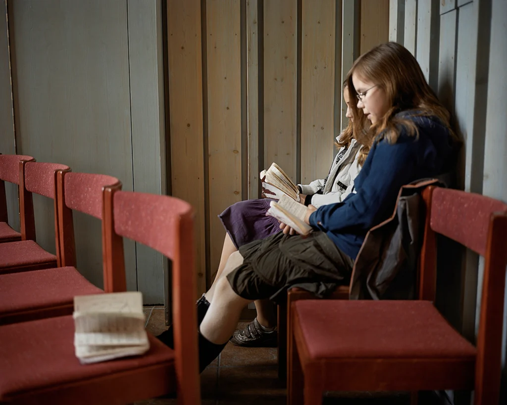 Två flickor sitter bredvid varandra och sjunger ur en psalmbok