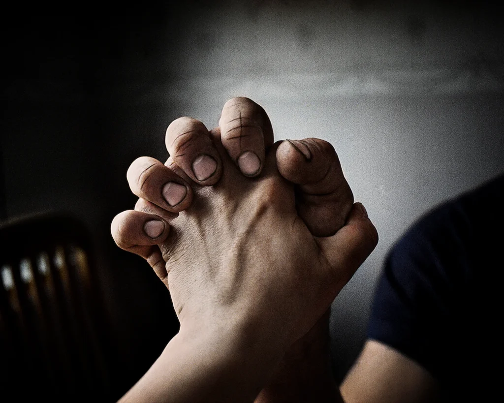 Två knäppta händer i närbild, det ser först ut som vid bön men det är armbrytning som pågår