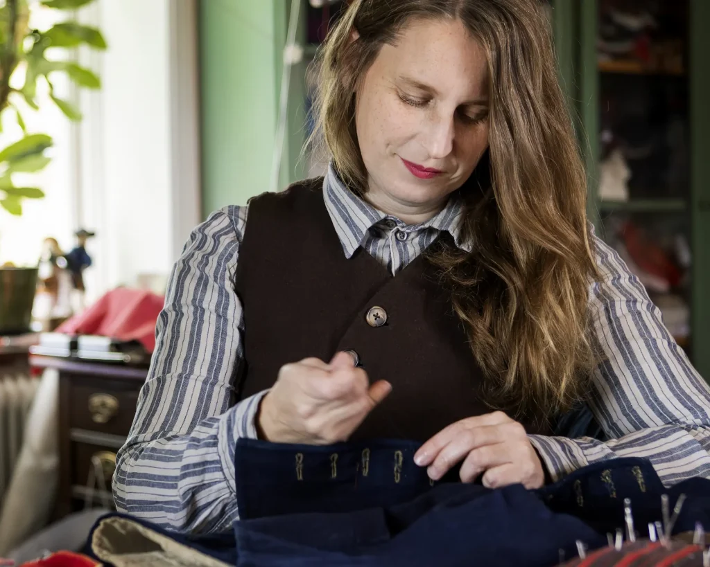 En kvinna sitter och syr för hand.