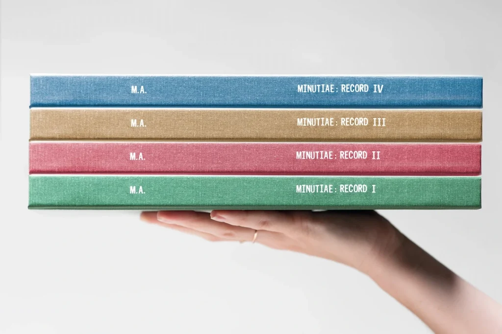 Fyra årsböcker med bilder hålls upp av en hand.